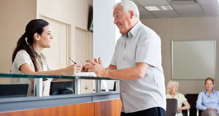 Great front desk customer service being received by older gentleman