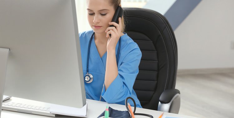 A medical assistant talking on the phone in front of her computer