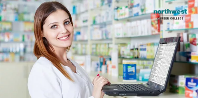 Pharmacy technician working with computer and smiling.