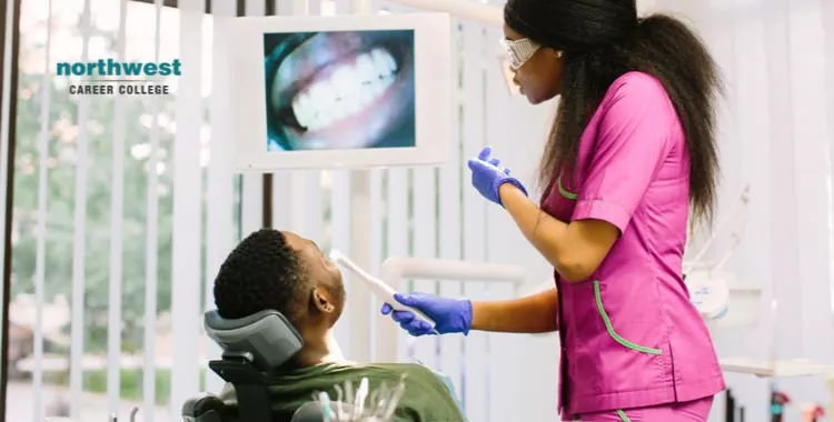 A female dental assistant using a camera to look at patient's teeth up close.