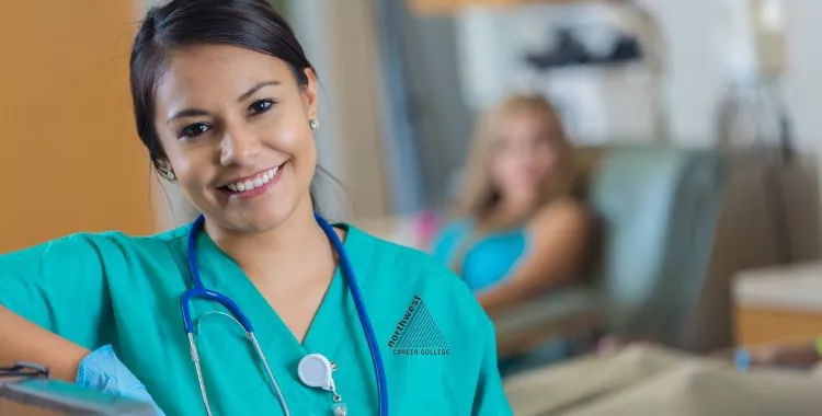 A Phlebotomist leaning against a tall furniture and smiling