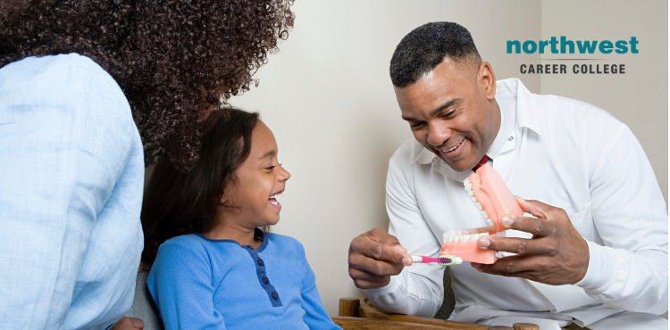 A man is showing a child the proper way to brush teeth with a prop in his hand.