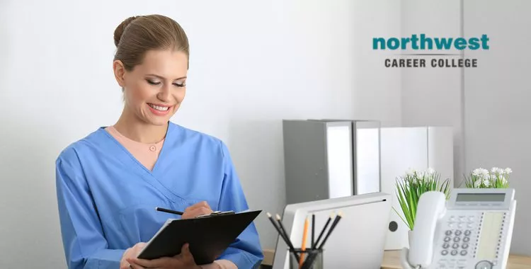 A medical administrative smiling ear-to-ear as she writes something on her clipboard.