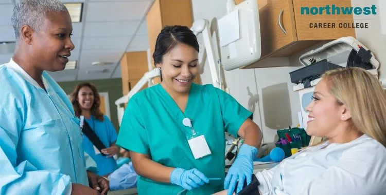 A medical intern learns how to draw blood from a smiling female patient.