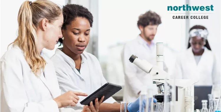 Pharmacy Technician students learning from tablet in front of a microscope.