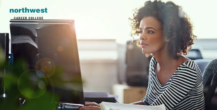 A woman on her computer looking intently at her monitor and working.