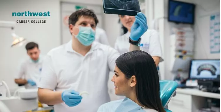 dental assistants looking at Xray of patient's teeth before procedure.