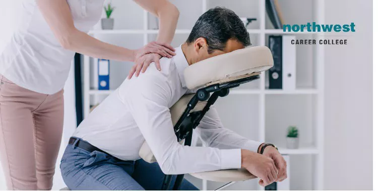 Man receiving massage from massage therapist in a specialized seat.