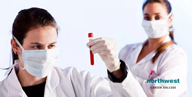 Female phlebotomist holding up blood sample in her left hand