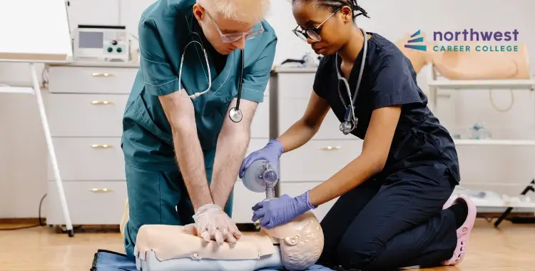 Two medical students practice CPR on a training mannequin in a classroom setting.