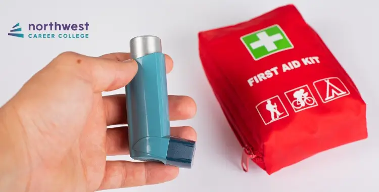 A hand holds an asthma inhaler next to a red first aid kit with a green cross symbol.