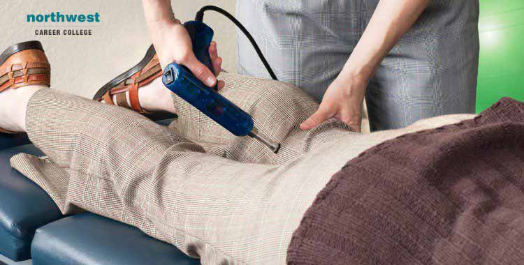 A therapist uses a massage gun on a clients thigh, raising the question: Do Massage Guns Really Work?
