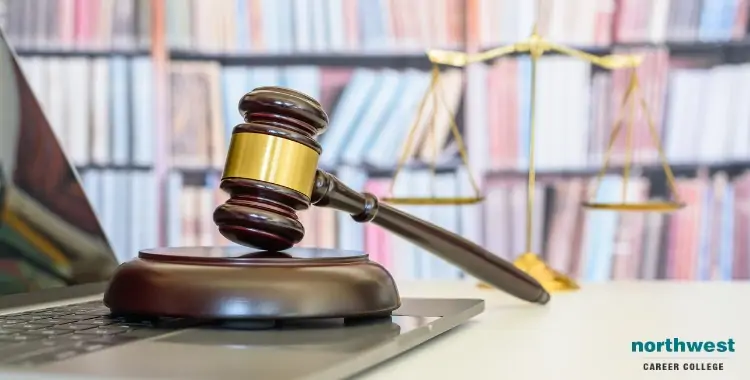A gavel rests on a laptop, symbolizing a Paralegal Career, with a scale of justice in the background.