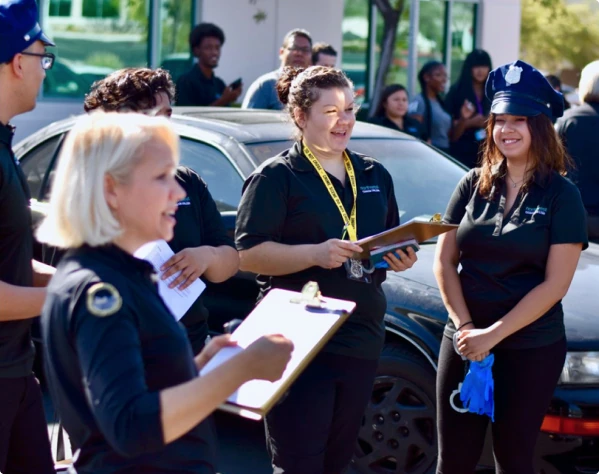 Students engage in a Criminal Justice Professional Degree program, discussing activities near a parked car.
