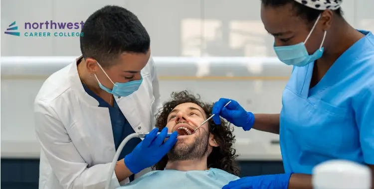 Two dental professionals assist a patient during a dental procedure in a clinical setting.