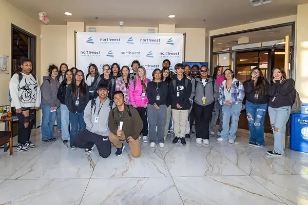 Group photo of students posing together in front of a Northwest banner in a lobby setting.