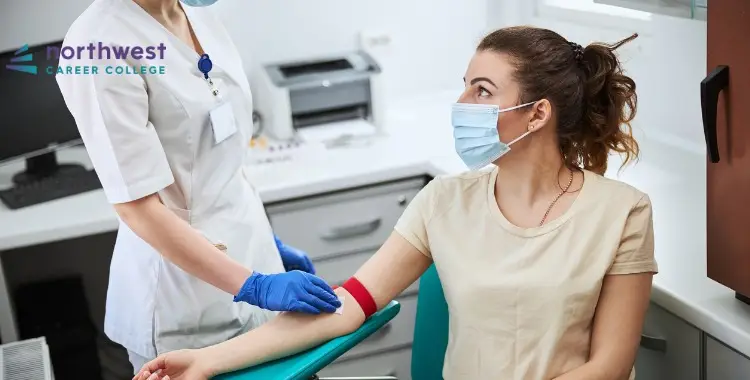 A healthcare worker prepares to draw blood from a patient in a clinical setting, both wearing masks.