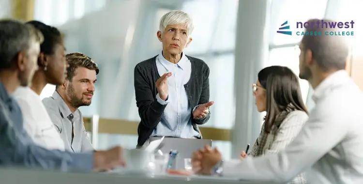 A diverse group of professionals in a meeting, with a woman presenting and engaging the team.