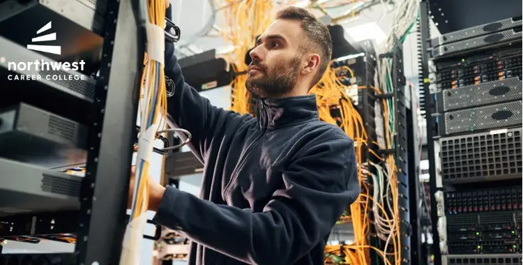 A technician works on server racks, managing cables in a data center environment.