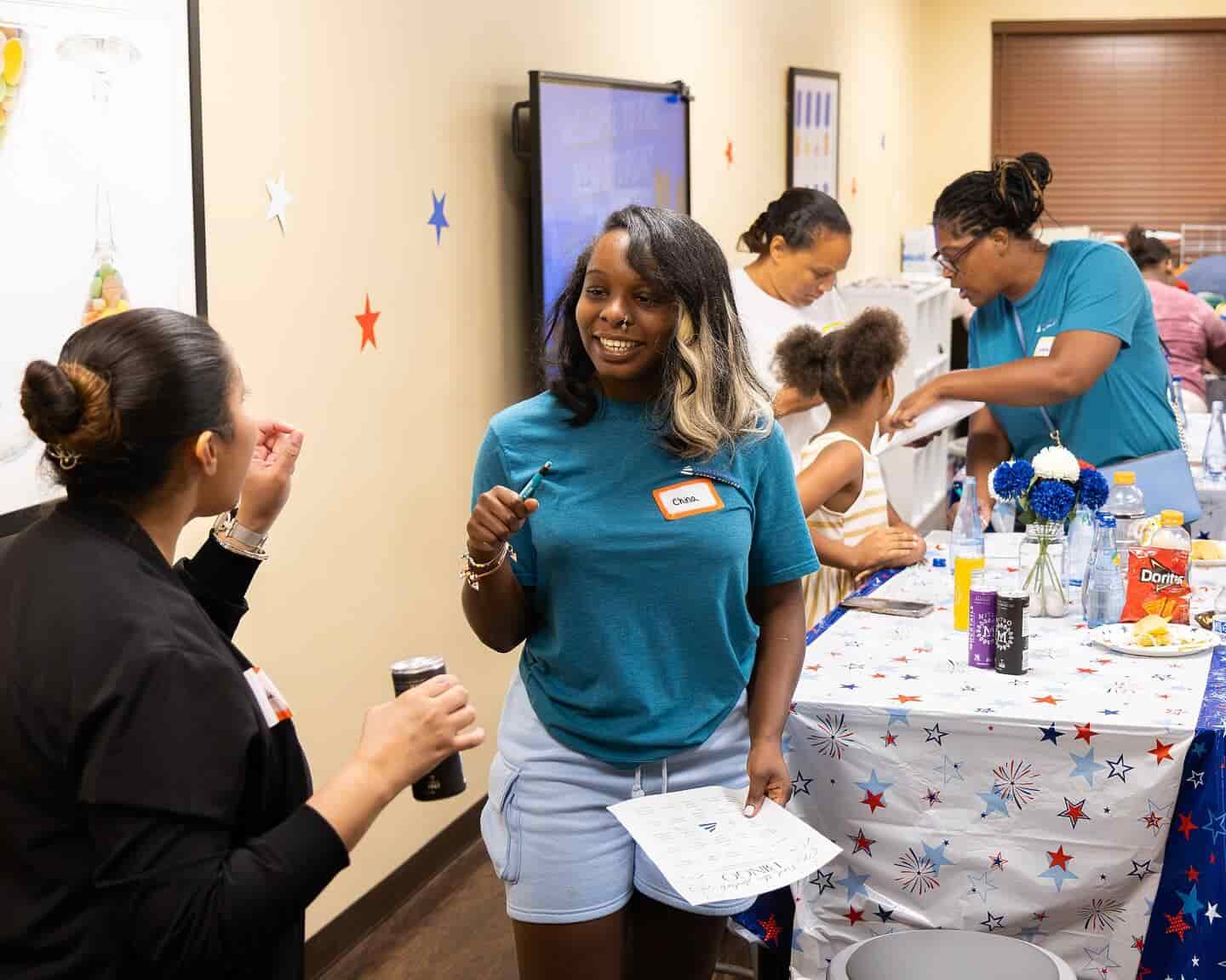 A group of people engage in a lively gathering, with snacks and drinks on a decorated table.
