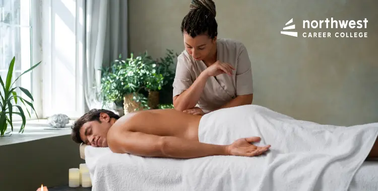 A massage therapist works on a clients back in a serene spa setting with plants and candles.
