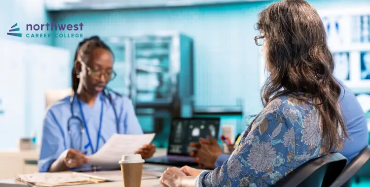 A healthcare professional discusses information with a patient in a clinical setting. Coffee cup on the table.