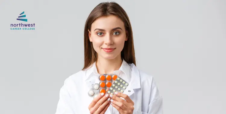 A woman in a lab coat holds various medication blister packs, smiling at the camera. Northwest Career College logo in corner.