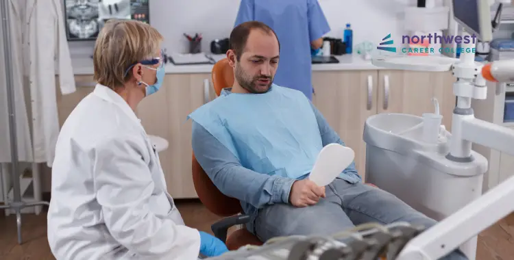 A patient sits in a dental chair, discussing with a dentist in a clinic setting.