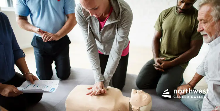 A group of people practicing CPR on a mannequin in a training session.