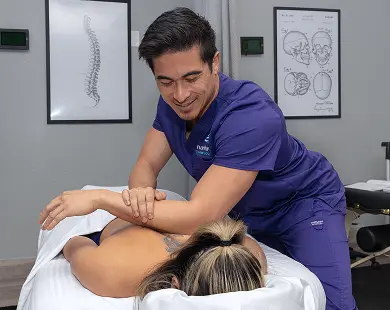 A massage therapist demonstrates techniques at a Las Vegas massage therapy school, focusing on client care.