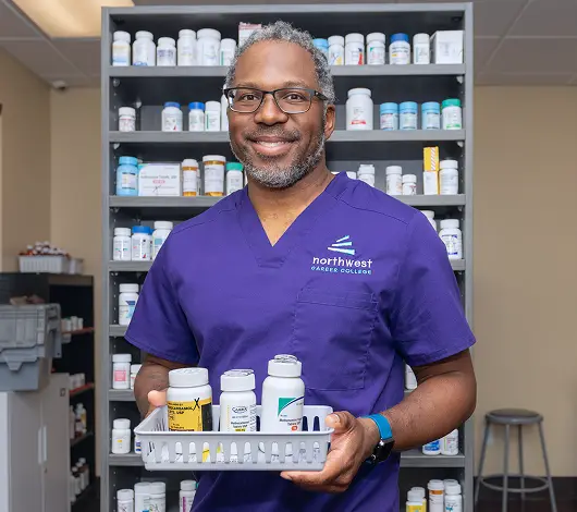 A pharmacy technician holds a tray of medication, showcasing skills from pharmacy tech programs at Northwest Career College.