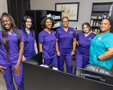 Group of six students in scrubs, smiling in a pharmacy setting, showcasing their pharmacy technician course experience.