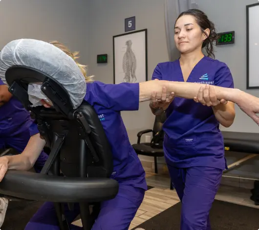 Students practice massage techniques in a classroom setting, highlighting schools with massage therapy programs.
