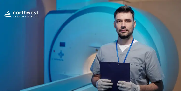 A healthcare professional in scrubs stands by an MRI machine, holding a clipboard in a clinical setting.