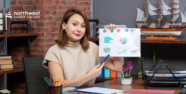 A woman in an office setting holds a report with charts, smiling and pointing with a pen. Books and a model ship are visible.