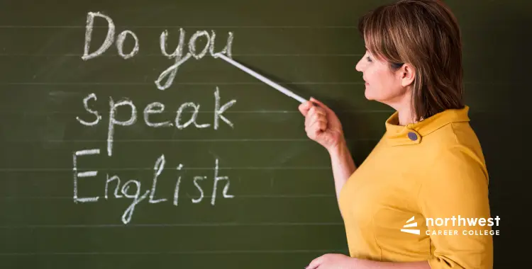 A woman in a yellow top points to Do you speak English written on a chalkboard.