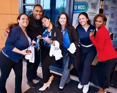 A group of six smiling individuals celebrates a BA Degree Program Outcome at an event.