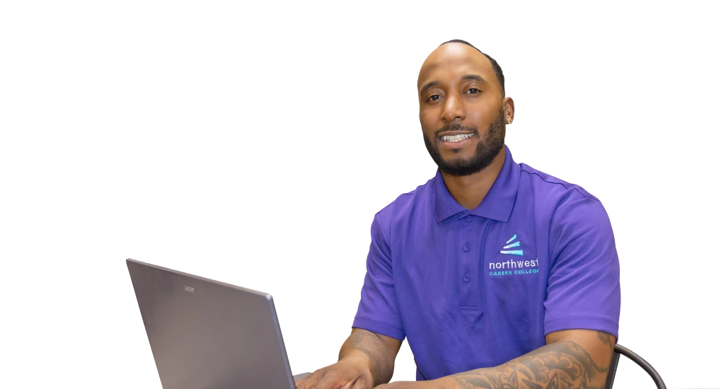 Smiling man in a purple shirt at a laptop, promoting the Business Administration Associate Degree Program at Northwest.
