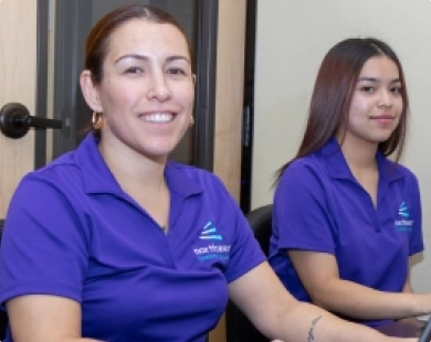 Two women in purple shirts smile at the camera, representing a business administrative assistant diploma in Las Vegas.