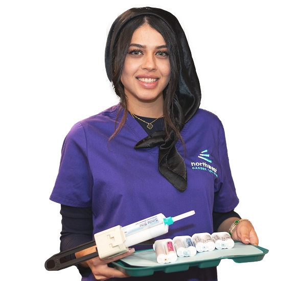 Smiling woman in purple scrubs holds dental tools, promoting the dental admin assistant program at Northwest Career College.