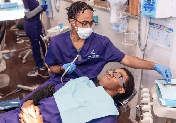 A dental assistant at a school in Las Vegas provides care to a patient in a modern dental clinic setting.