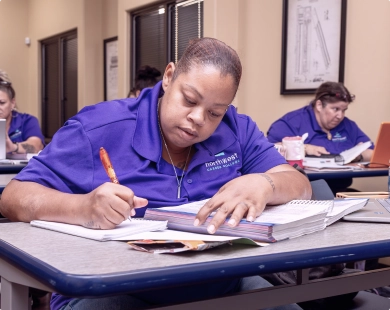 Students studying in a classroom at a medical billing coding school, focused on their work and taking notes.