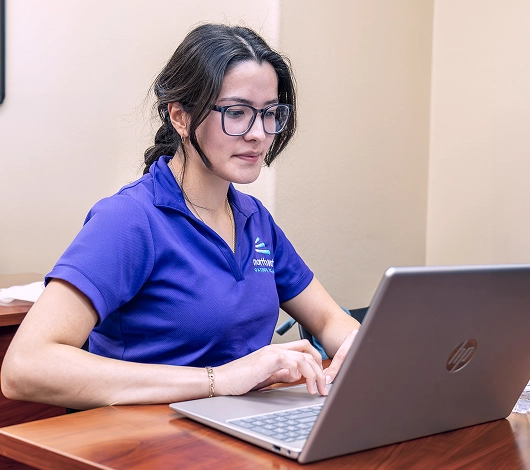A paralegal student in the class focuses on her laptop, engaged in her studies.