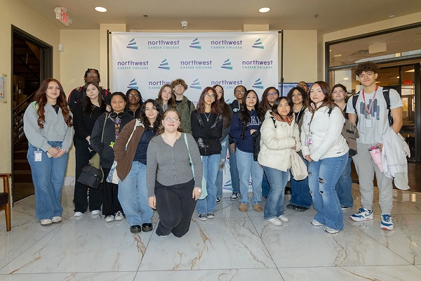 Group photo of students posing together in front of a Northwest Career College backdrop.