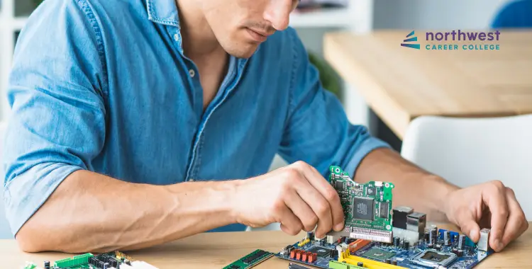 A person assembling computer components on a table, focused on a circuit board. Northwest Career College logo in the corner.