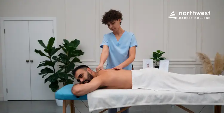 A massage therapist gives a back massage to a male client on a treatment table in a serene setting.