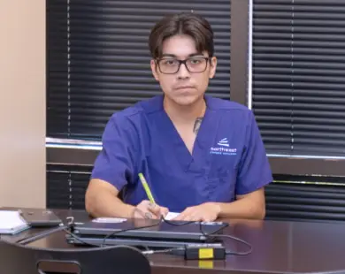 Student in scrubs studying at a desk, highlighting the healthcare administration online program.