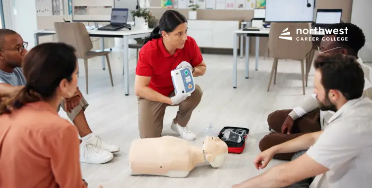 A trainer demonstrates CPR techniques on a mannequin to a group of attentive students in a classroom setting.