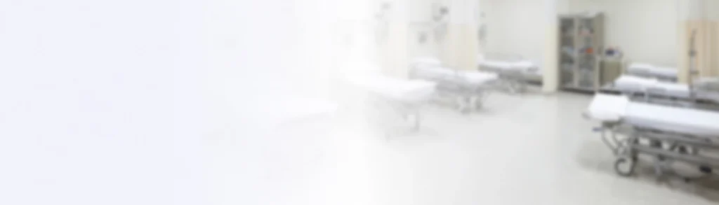 A blurred hospital room with empty beds and medical equipment in a clean, bright environment.