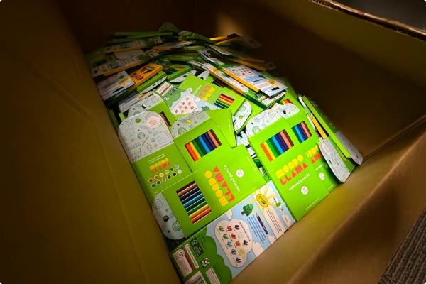 A cardboard box filled with colorful art supplies and packaging, primarily in green.